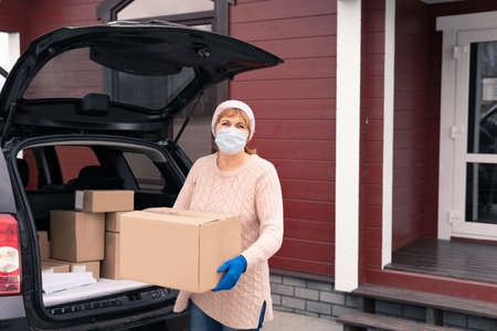 Delivery man holding cardboard boxes in medical rubber gloves.の写真素材