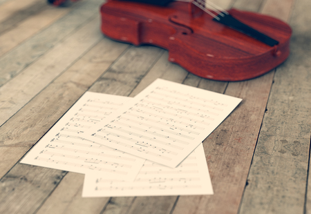 sheets music and a violin on wooden background (3d render)の写真素材