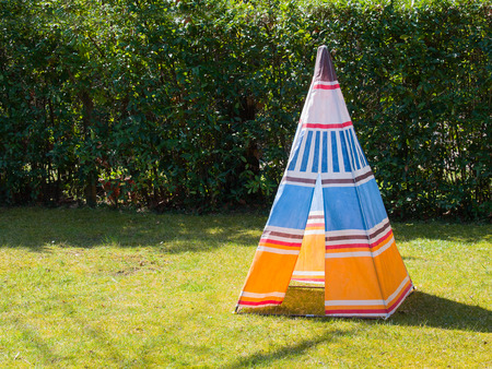 Colorful child's toy Teepee tent of native american made of canvas on the grass in a sunny day