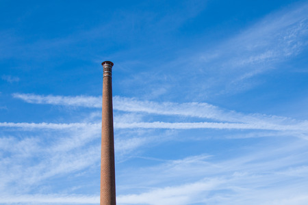 Old tall chimney made of bricks. long and thin clouds in the sky