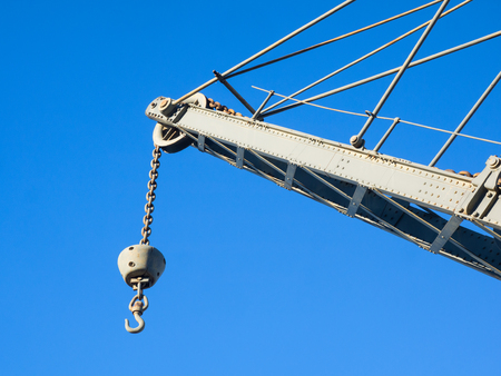 Details of upper part of an old crane: hook, chain, pulley, beam, rivets 