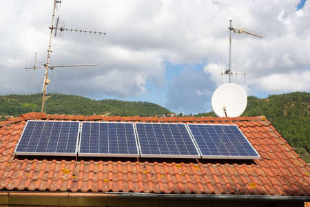 solar panels and antennas on the roof of a house in the countryside. hills covered with woods in the...