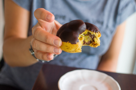 a female hand grabbing a tasty chocolate eclairs italian food