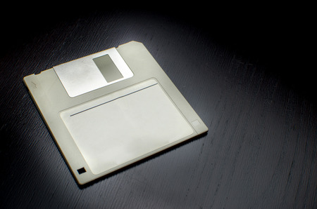 grey floppy disk empty label with black wooden desk background