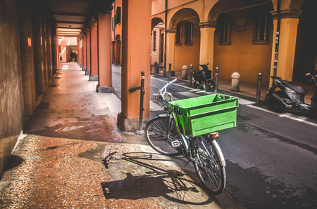 Bologna, Italy, April 25 2016: parked bicycle on narrow street along an empty portico