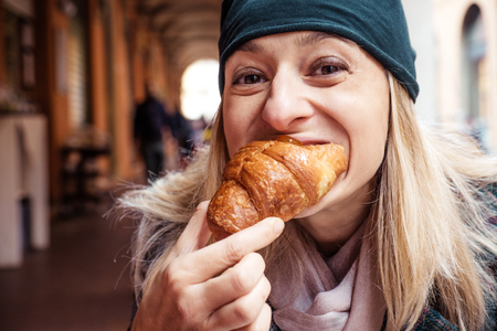 woman bite croissant outdoor bar breakfastの写真素材