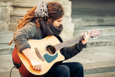 Bologna, Italy, 5 Jan 2016 - Rasta guitar player focused play in Piazza Maggiore square