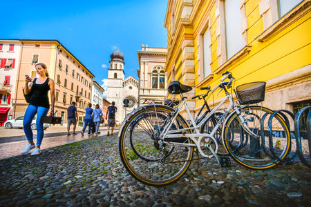 bicycles parked near the Trento cathedral, a girl walk while looking her smartphone - Trento, Italy, 14 Aug 2017のeditorial素材