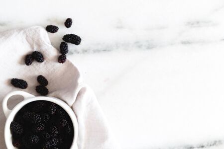 Blackberries on a white marble surface.