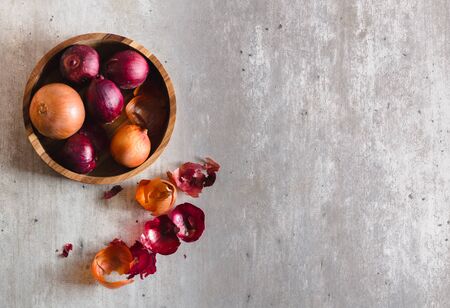 Onions in a baking sheet with salt and on a gray surface.の写真素材