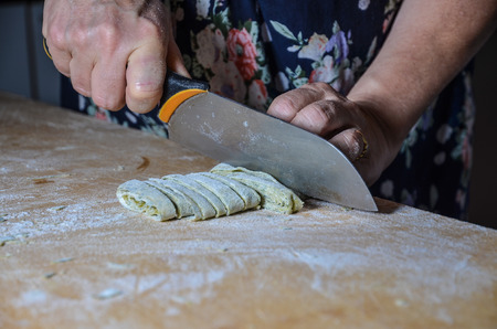 grandma cutting fresh nettle flavoured pasta with knifeの写真素材