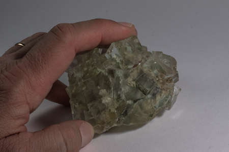 mineral sample of green fluorit held by two fingersの写真素材