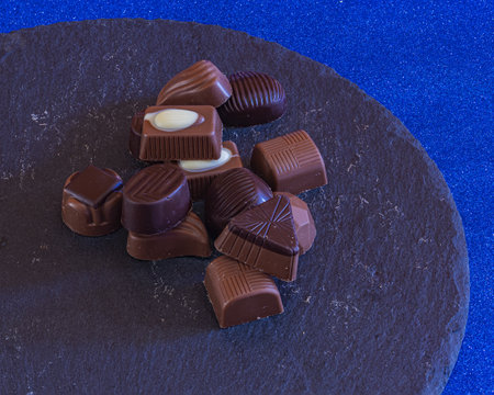 filled chocolate candies various assorted flavors on stone plateの写真素材