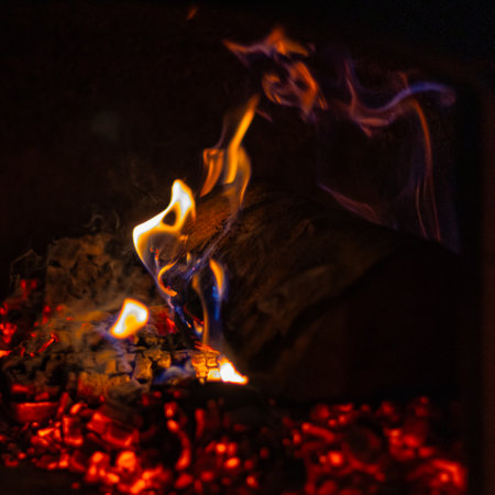 Burning Firewood in Cozy Hearth: Flames Flickering in Rustic Fireplaceの写真素材