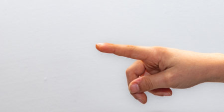 Close-up of a human hand with one finger extended, pointing right against a stark white background, perfect for concepts of direction, choice, or pointing out specific detailsの写真素材