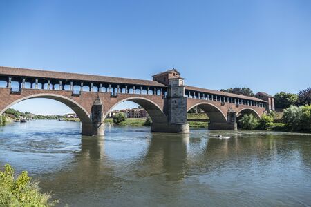 The covered bridge with red bricks over the Ticino river in Paviaの写真素材