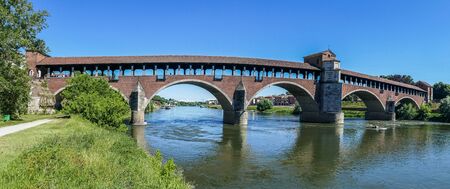 The covered bridge with red bricks over the Ticino river in Paviaの写真素材