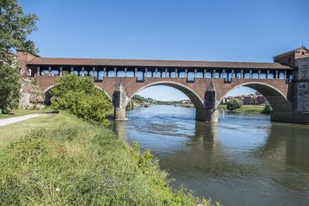 The covered bridge with red bricks over the Ticino river in Paviaの写真素材