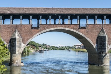 The covered bridge with red bricks over the Ticino river in Paviaの写真素材