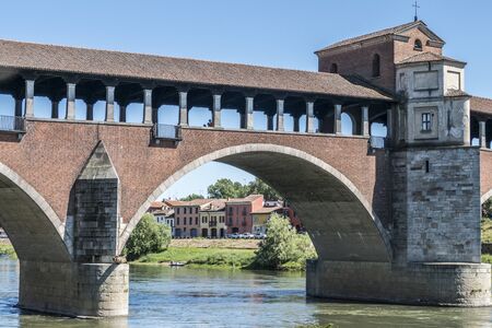 The covered bridge with red bricks over the Ticino river in Paviaの写真素材