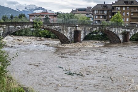 swollen river after a storm with the waters touching the bridgeの写真素材