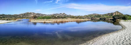 ultra wide panorama of a mountains reflected in a lake in Sardinia in Cala Berchidaの写真素材