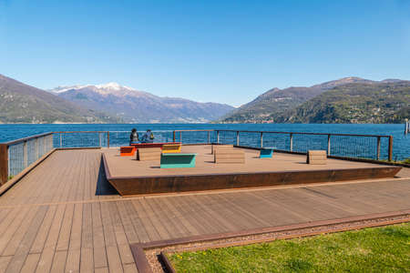 Luino viewpoint on Lake Maggiore with two tourists sitting on a benchの写真素材