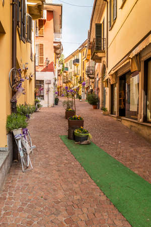 Luino, Italy - 04-19-2021: Beautiful street in the historic center of Luino with shops, plants and flowersのeditorial素材