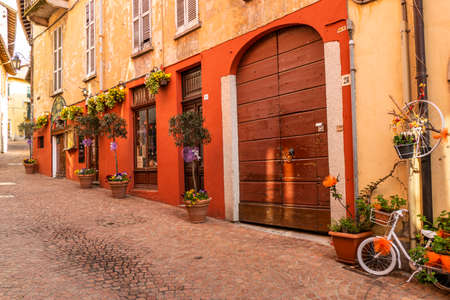 Luino, Italy - 04-19-2021: Beautiful street in the historic center of Luino with shops, plants and...