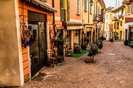 Luino, Italy - 04-19-2021: Beautiful street in the historic center of Luino with shops, plants and flowersのeditorial素材
