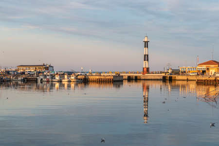 Cattolica, Italy - 04-08-2021: The port of Cattolica with the boats and the lighthouse reflecting in the water at sunsetのeditorial素材