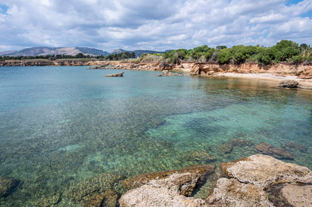 Beautiful beach with crystal clear water and a natural rock arch in the background in Syracuse Sicilyの写真素材