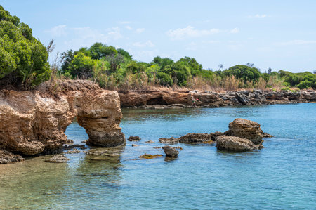 Beautiful beach with crystal clear water and a natural rock arch in Sicily in Syracuseの写真素材