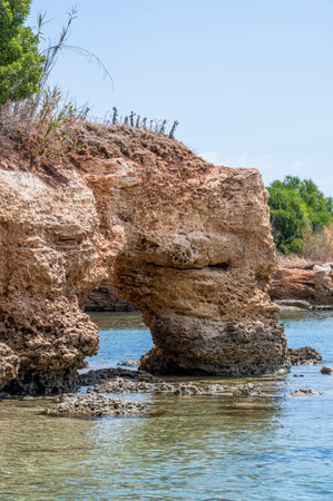 Beautiful beach with crystal clear water and a natural rock arch in Sicily in Syracuseの写真素材