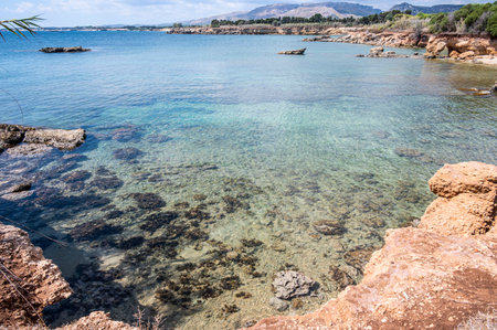 Beautiful beach with crystal clear water and a natural rock arch in the background in Syracuse Sicilyの写真素材