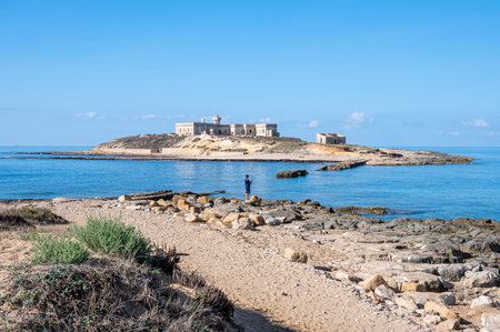 The Island of Correnti in Portopalo in Sicily with a man that take a photoの写真素材
