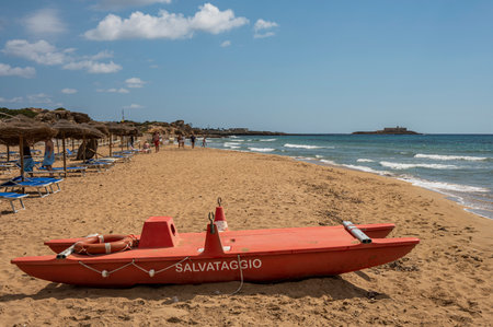 Portopalo, Italy - 09-17-2022: Beautiful beach with sand, turquoise and green water is a red patino in the foreground in Portopalo di Capo Passeroのeditorial素材