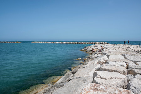 Fano, Italy - 06-22-2022: Rocks on the beach of Fano with fishermenのeditorial素材