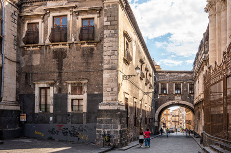 Catania, Italy - 09-23-2022: Beautiful street with historic buildings and a stone arch in Cataniaのeditorial素材