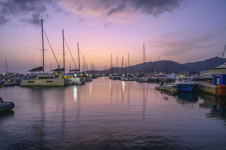 Beautiful twilight seen from a small sea port with boats, lights and predominance of purple colorの写真素材