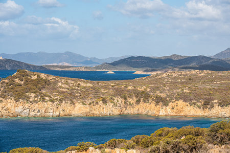 Landscape of the south-west coast of Sardinia with cliffs, blue sea, fjords and white cloudsの写真素材