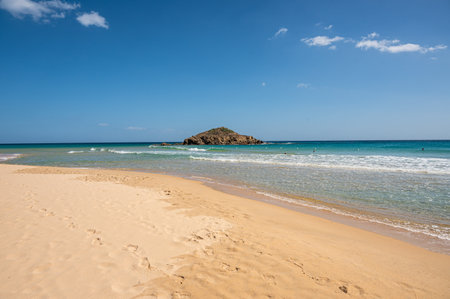 The beautiful beach of Su Giudeu in the south of Sardinia with transparent and turquoise water and a small island in front of the bayの写真素材