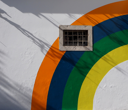 Old railed window with painted rainbow on the wall aroundの写真素材
