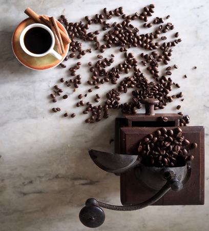 Grinder, coffe beans and a coffee cup on a marble table