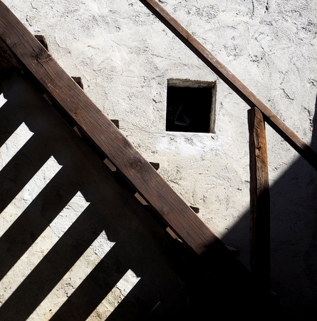 Old wooden staircase with long shadows against the wall of a rural houseの写真素材