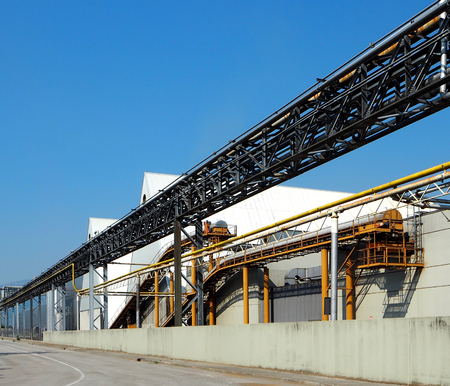 Conveyor belts, buildings and pipes in an industrial siteの写真素材