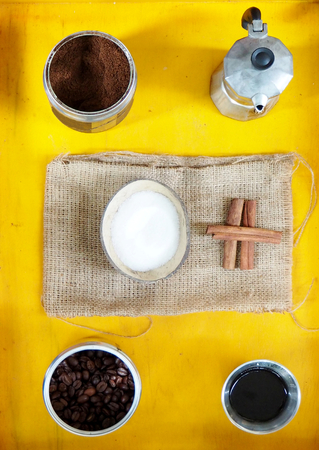 White sugar, coffe and cinnamon sticks on a yellow tableの写真素材