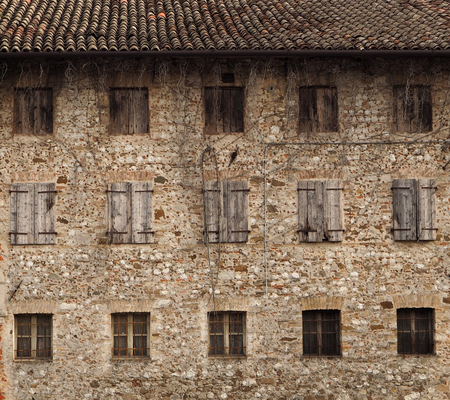 Natural stone facade of an old rural house with three files of windowsの写真素材