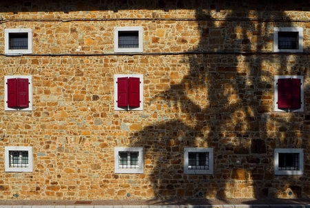 Natural stone facade of a rural house with a tree shadow on itの写真素材