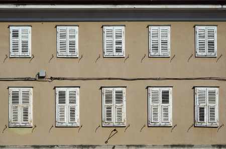 Traditional european wooden shutters on a brown facade of an old residential buildingの写真素材